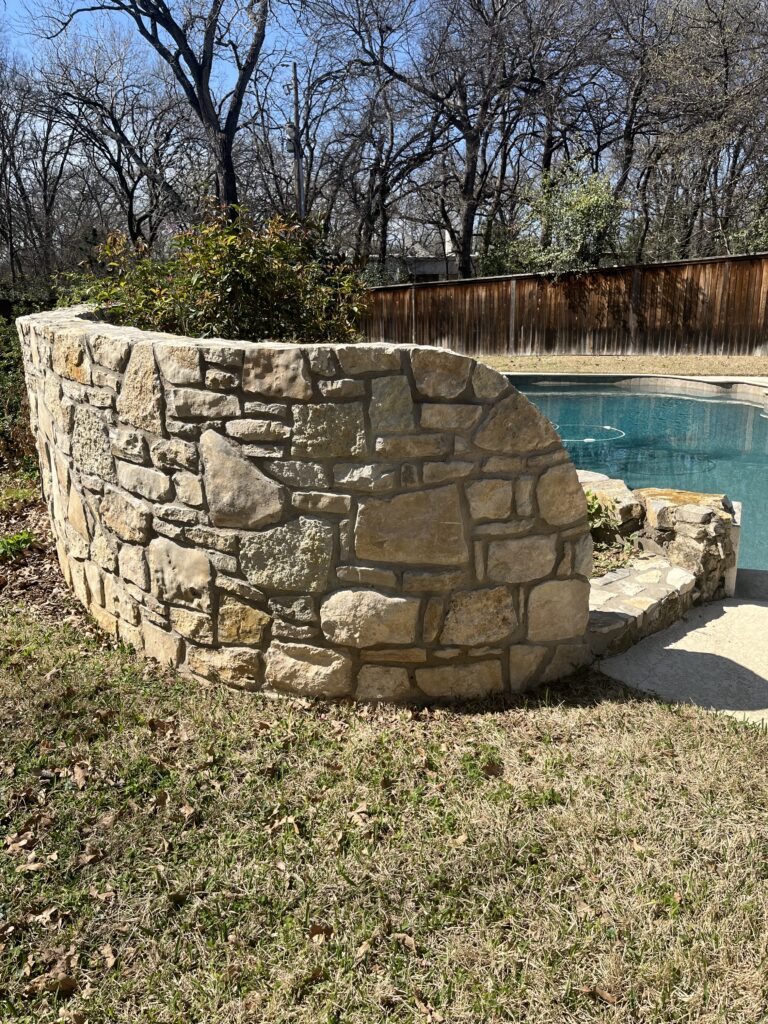 This beautiful irregular Granbury limestone screen wall was constructed of reclaimed stone and made a beautiful backdrop to the swimming pool.